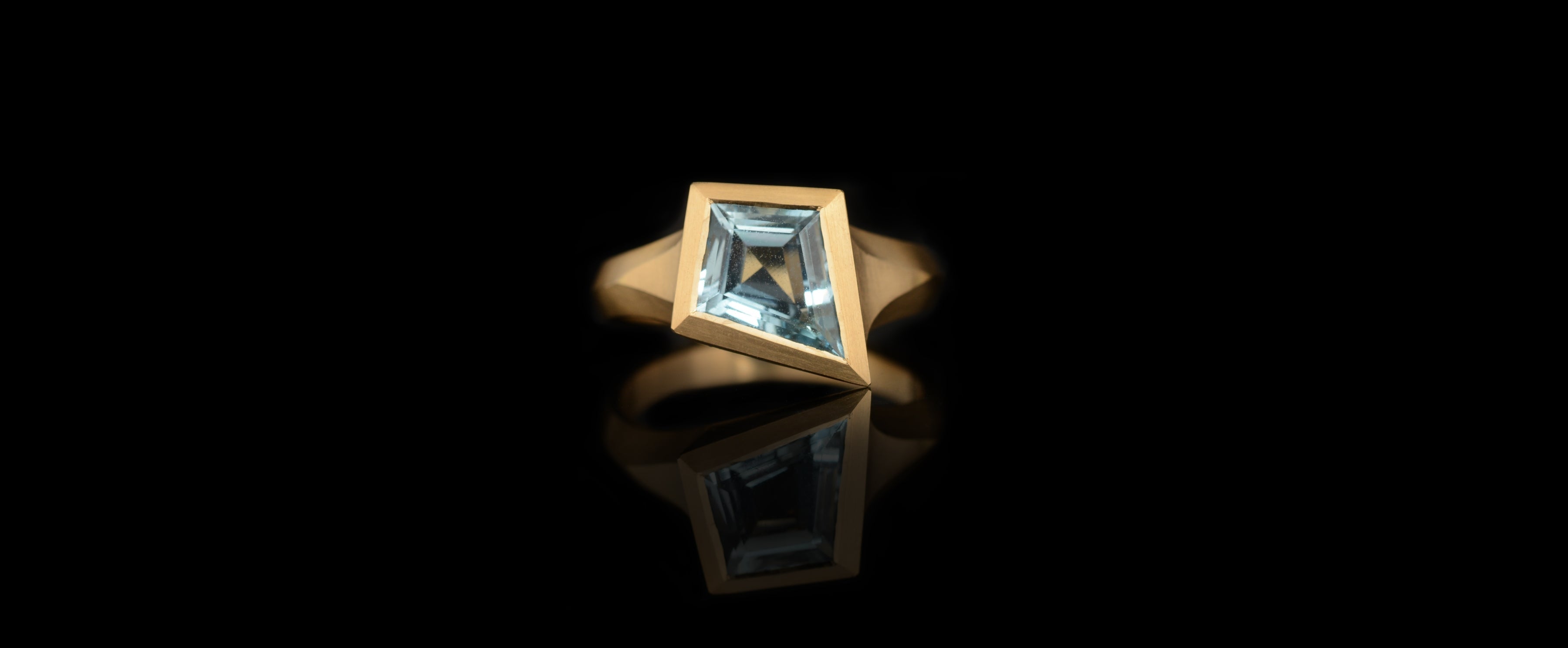 Kite shaped aquamarine yellow gold aegis carved ring